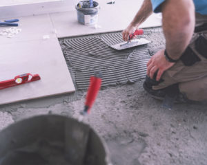 Man applying tile adhesive on the floor