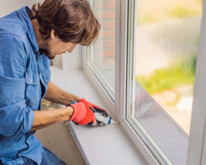 Man in a blue shirt does window installation